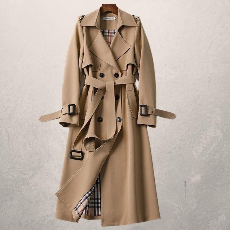 A beige trench coat with a belt, button detailing, and adjustable straps on the cuffs. It has a classic plaid lining and hangs against a neutral background.