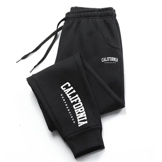 Warm Sports Casual Ankle Banded Pants in black are crafted from polyester and feature a drawstring waistband. These stylish pants showcase prominent white text saying "CALIFORNIA San Francisco" on the left leg, combining casual comfort with a high-waist design for enhanced style.