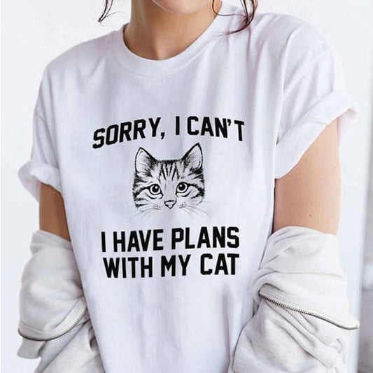 A person is wearing a CJ'S Women's Cute Summer Print Graphic Tee Shirt in white with rolled-up sleeves, featuring an illustration of a cat's face and the text "Sorry, I can't, I have plans with my cat." The person is also donning a light-colored jacket draped partially off their shoulders.