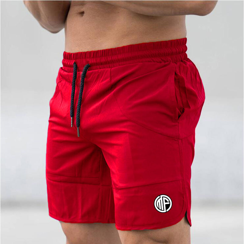 A person wearing Men's Quick-Dry Swim Shorts with Pockets, featuring a black drawstring and a circular logo on the left leg, stands in a neutral pose. The vibrant red color of the shorts is accentuated by the blurred grey background, highlighting their active lifestyle.