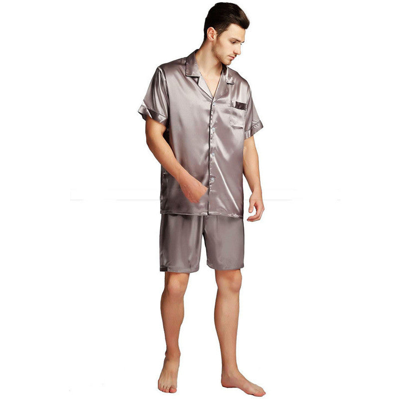 A man barefoot, dressed in a glistening Men's Silk Satin Pyjama Set, featuring long sleeves and shorts.