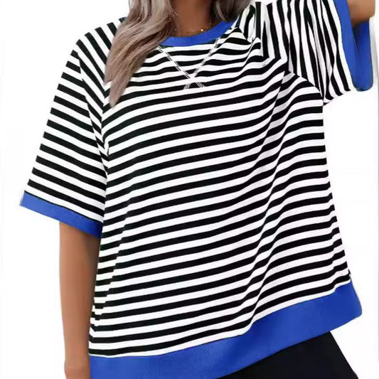 A person wearing the Zendrop Women's Casual Versatile Striped Loose T-shirt, characterized by its black and white stripes, blue trim on the sleeves and bottom hem, and short sleeves. Made from polyester fiber, this shirt features a loose fit that reflects Japanese and Korean casual style. The individual has long, wavy hair with their face not visible.