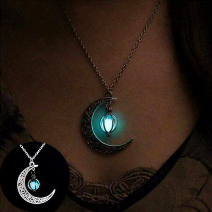 A CJ'S Luminous Crescent Moon Necklace with Glowing Orb Pendant hangs around a person's neck. The crescent moon, decorated with intricate patterns, encases a glowing blue orb. An inset image shows a close-up of this mystical jewelry's details.