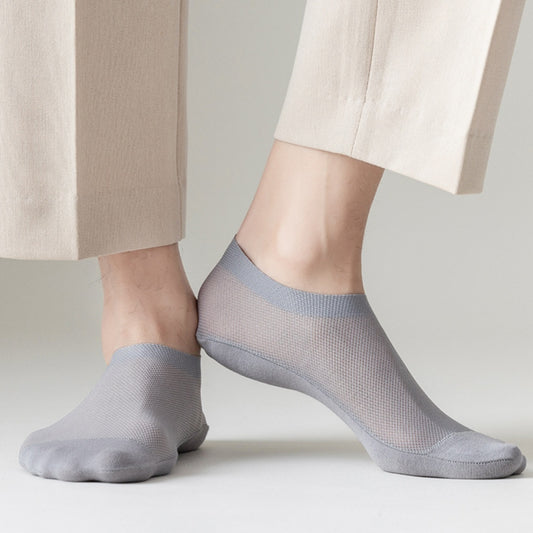 Close-up of two feet wearing Zendrop's Men's Mesh Breathable Pure Cotton Invisible Socks in light grey, paired with beige pants. The image highlights the breathable, mesh-like fabric of the combed cotton socks and their smooth, snug fit around the feet and ankles.