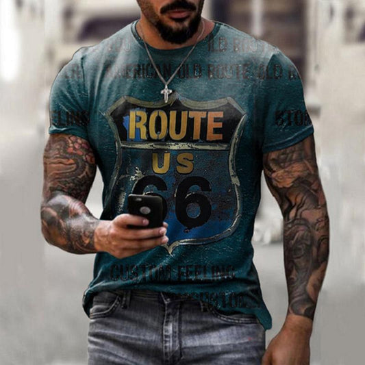 A muscular man with tattoos strides along, absorbed in his phone. He wears a Men's Vintage Route 66 Graphic T-Shirt - Classic and Comfortable and a cross pendant necklace. The background stays blurred, emphasizing his rugged look.