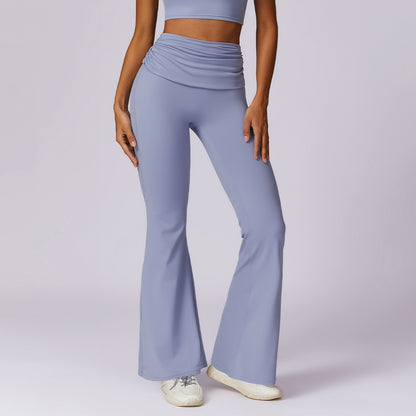 A person dressed in light purple quick-dry hip-raising yoga pants, featuring a casual wide-leg and nude feel, along with a matching crop top, is standing with one hand on their hip. They are also sporting white sneakers against a plain, light-colored backdrop.