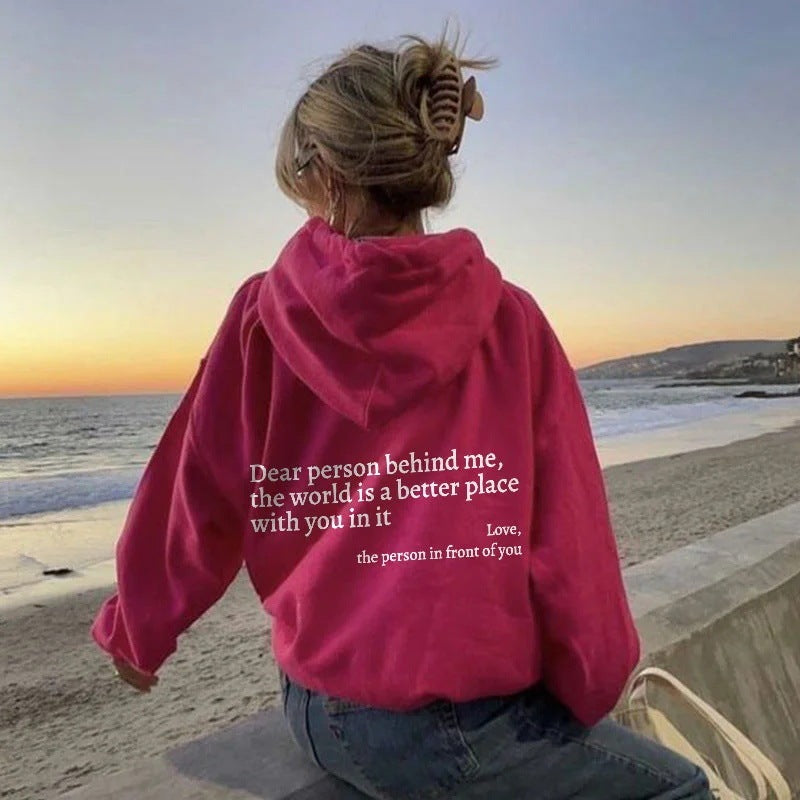 Woman in pink hoodie with inspirational quote on the beach