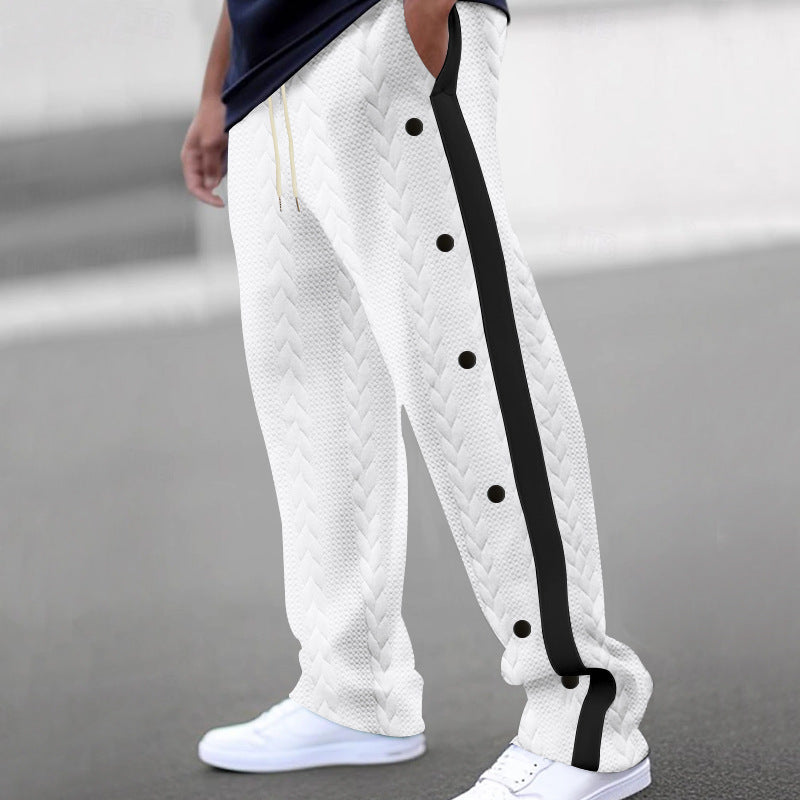 A person is wearing Zendrop's Men's Fashionable Jacquard Button Casual Pants in white cotton blend, featuring a black side stripe and black buttons along the side seam. The loose-fitting sweatpants showcase a textured jacquard pattern and are paired with white sneakers. The individual is standing outdoors on a paved surface.