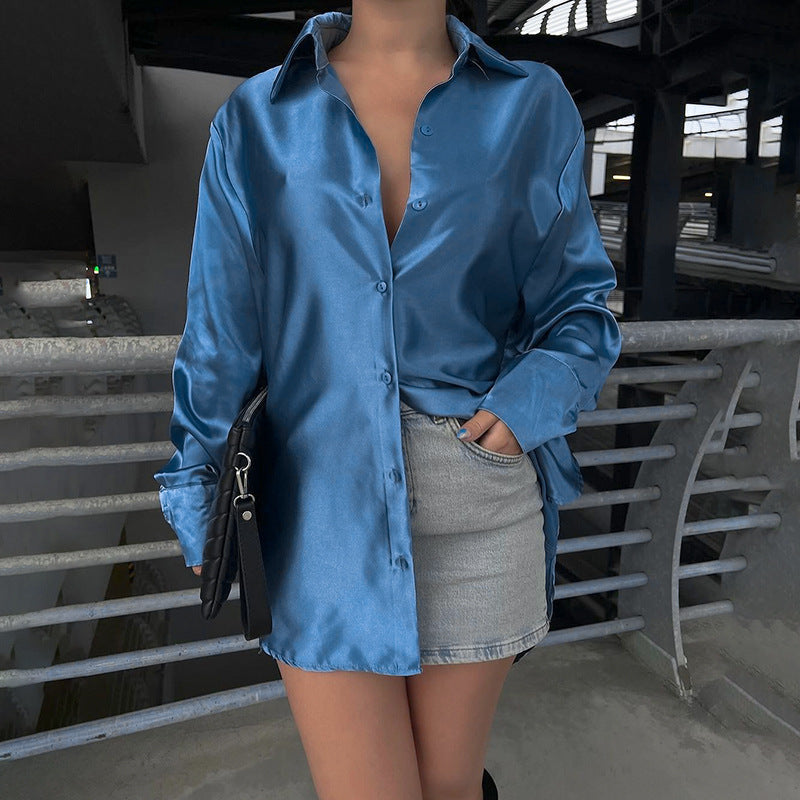 A person exudes a chic, urban vibe in the Graceful slim-fit satin shirt with its glossy European and American style, paired with a short denim skirt. Holding a black clutch bag, they stand confidently against a railing, embodying the understated elegance of a true Private Clothing Socialite.