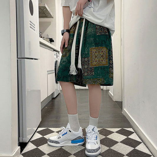 A person wearing an oversized white t-shirt, CJ's Casual Fashion Men's Sports Beach Pants featuring a cartoon pattern tied at the waist with a long white drawstring, white socks, and white sneakers with blue accents stands on a black-and-white checkered floor in a modern kitchen setting.